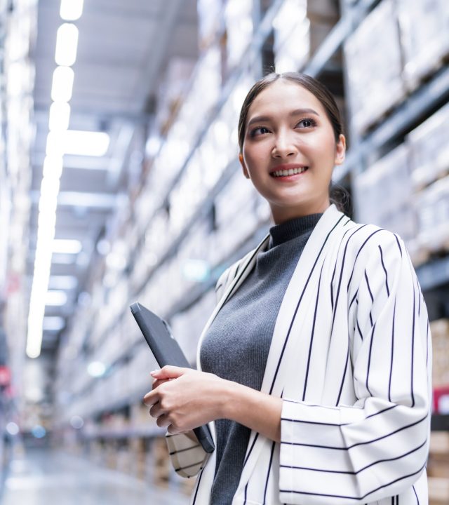 Portrait of asian woman business owner using digital tablet checking amount of stock product inventory on shelf at distribution warehouse factory.logistic business shipping and delivery service